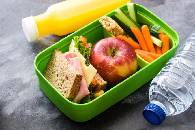 Brotdose mit Sandwich, Apfel, Karotten, Gurke und Getränk für eine ausgewogene Schuljause