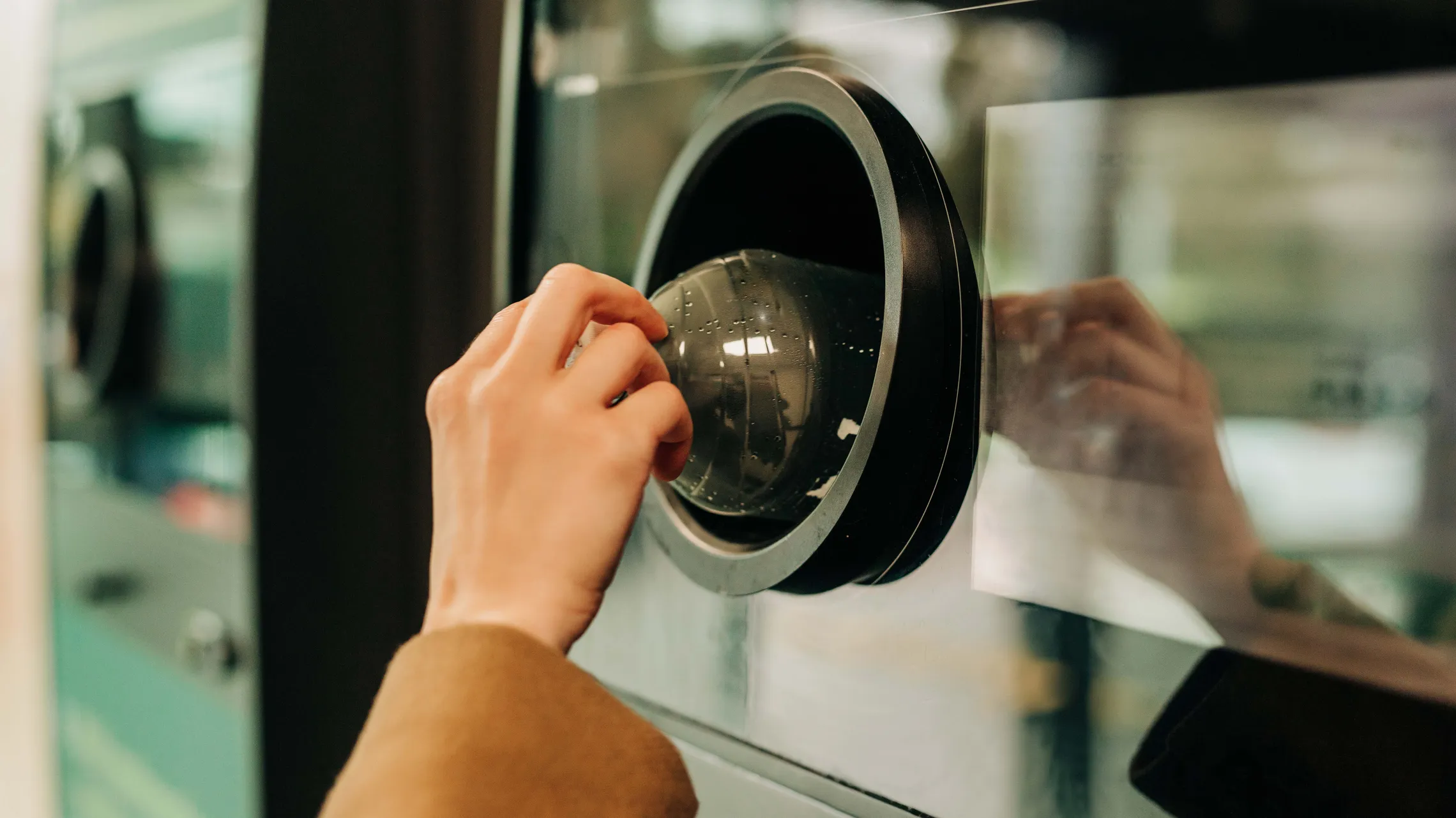 Eine Hand wirft eine leere Plastikflasche in einen Recyclingautomaten und zeigt damit, wie man umweltbewusst handelt.