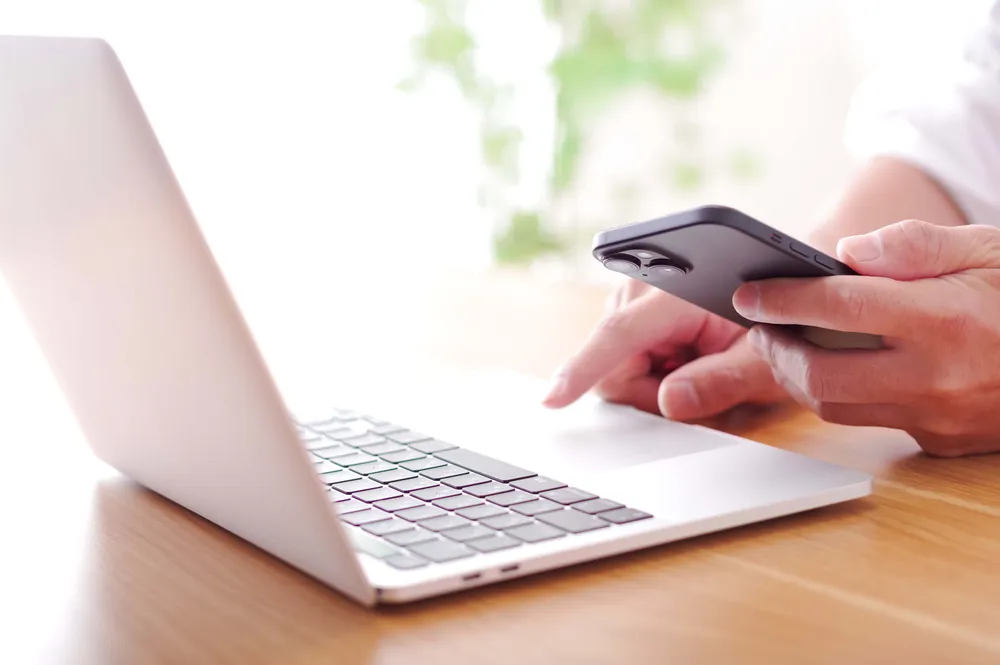 Person nutzt Smartphone und Laptop für eine Online-Bestellung oder Sendungsverfolgung
