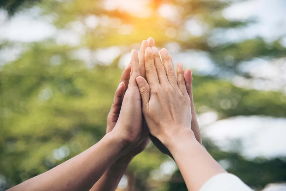 Mehrere Hände treffen sich als Symbol für Teamwork, Zusammenhalt und erfolgreiche Zusammenarbeit