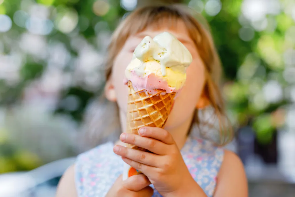 Ein Mädchen isst Eis mit einer Eistüte und drei Kugeln