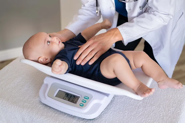 Ärztin untersucht ein Baby auf einer digitalen Waage
