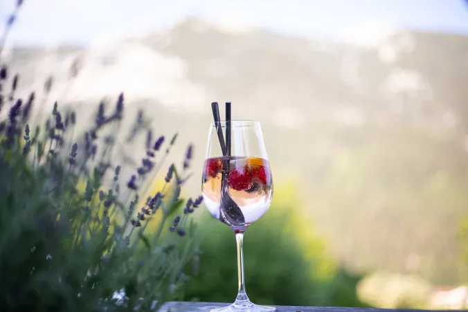 Ein Glas Lillet steht vor einem Lavendelstrauch.