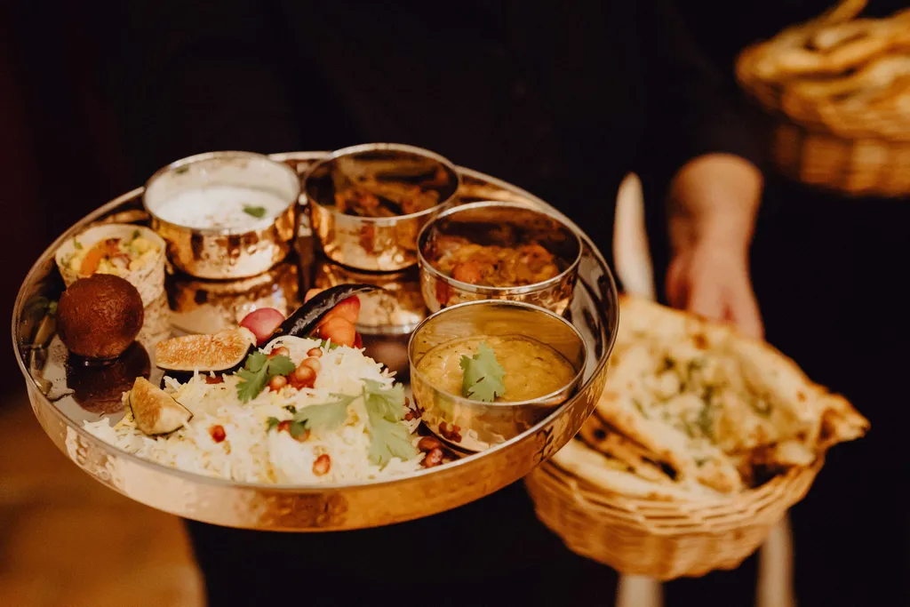 Indisches Thali mit Reis, Currys, Naan-Brot und traditionellen Beilagen