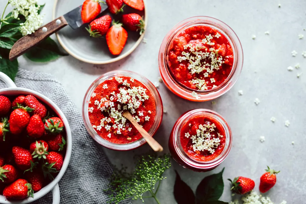 Gläser mit Erdbeer-Holunder-Marmelade und frischen Erdbeeren
