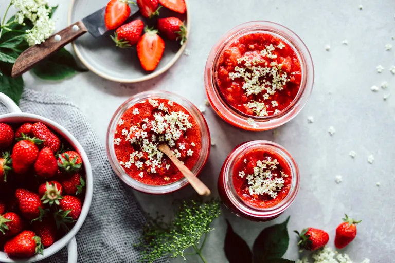Gläser mit Erdbeer-Holunder-Marmelade und frischen Erdbeeren