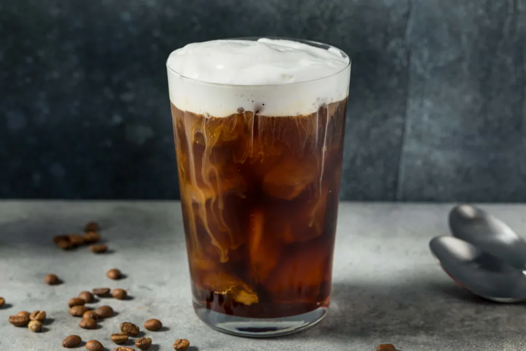 Cold Brew Coffee mit cremigem Milchschaum und Eiswürfeln im Glas