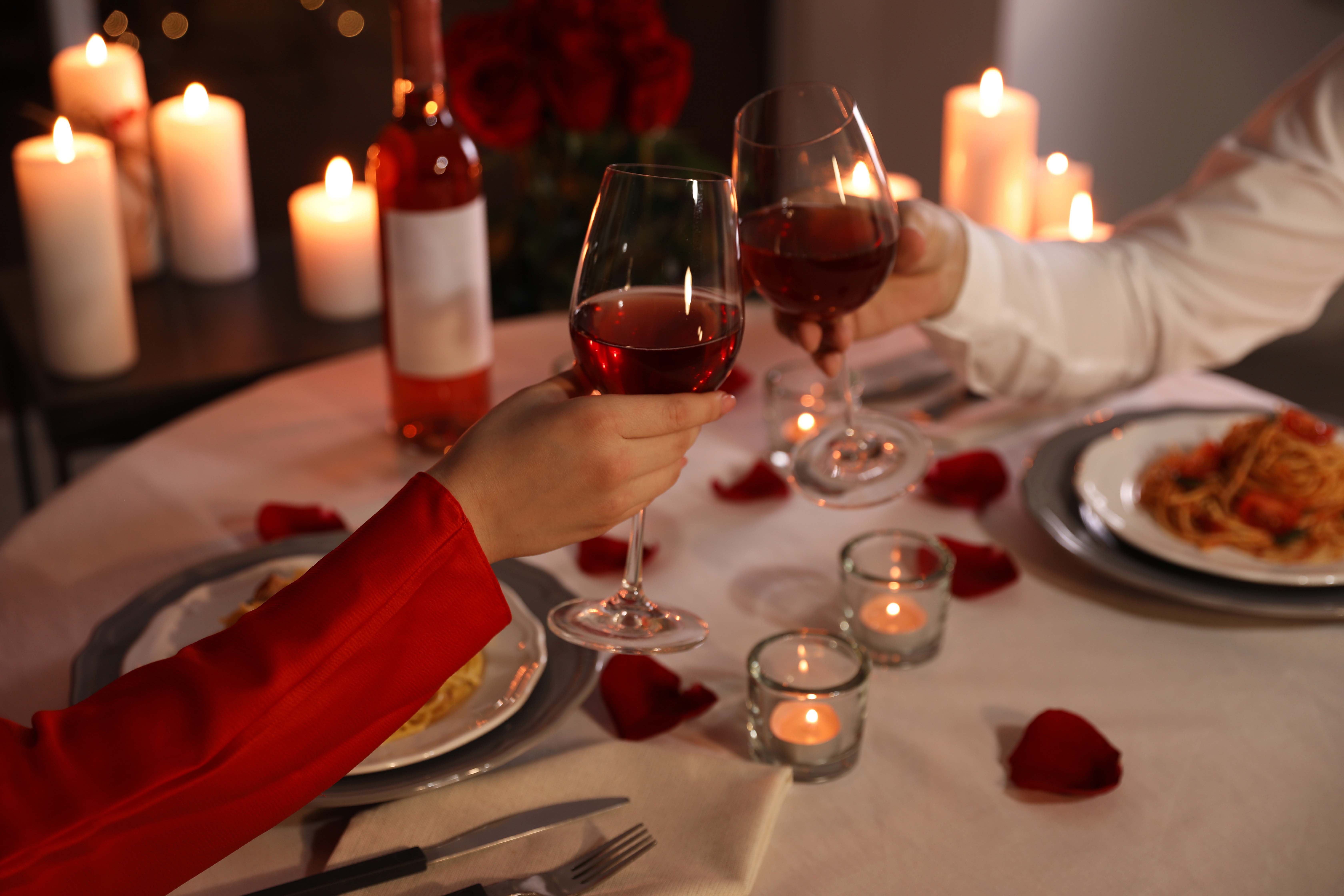 Candlelight Dinner Ein Paar ein einem Esstisch mit Kerzen. Anstoßen mit Rotwein