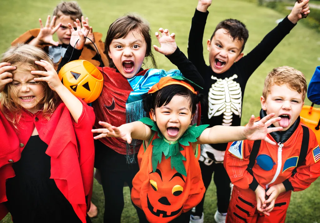 Kinder in Halloweenkostümen machen gruselige Gesten in die Kamera