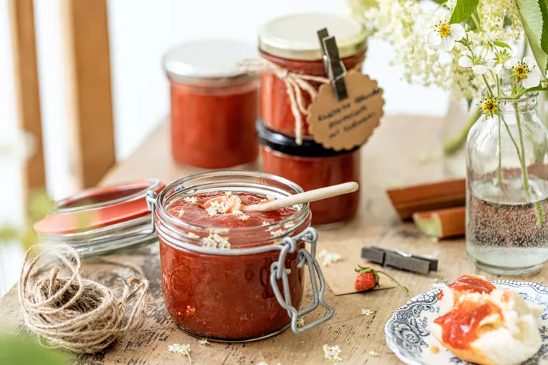 Selbst gemachte Erdbeer-Holunder-Konfitüre im Bügelglas mit frischen Erdbeeren und Holunderblüten