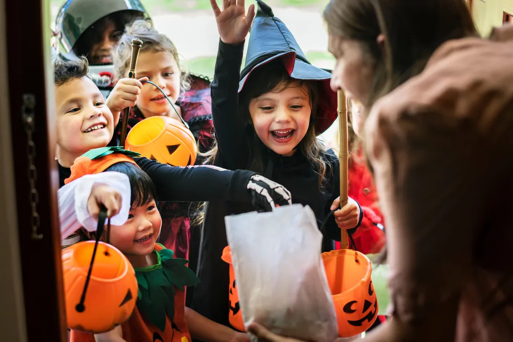 Eine Gruppe Kinder zieht zu Halloween von Haus zu Haus und verlangt Süßigkeiten