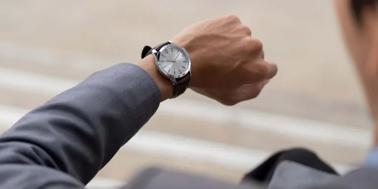 Person im Business-Outfit blickt vor einem Termin auf ihre Armbanduhr