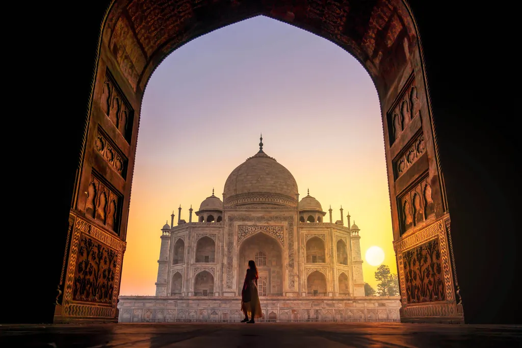 Blick durch ein Tor auf das Taj Mahal bei Sonnenaufgang in Indien