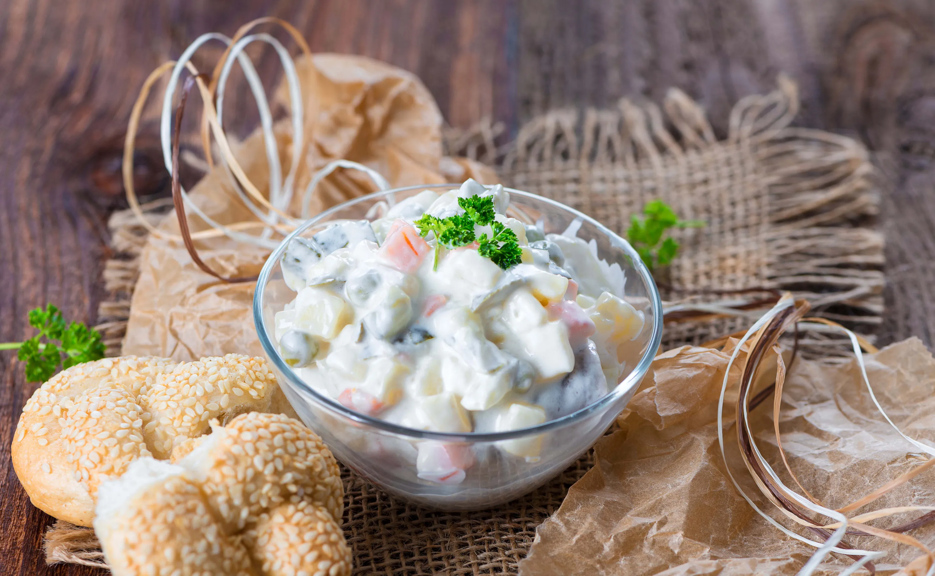 Schüssel mit Heringsschmaus-Salat und Sesamgebäck auf rustikalem Holztisch