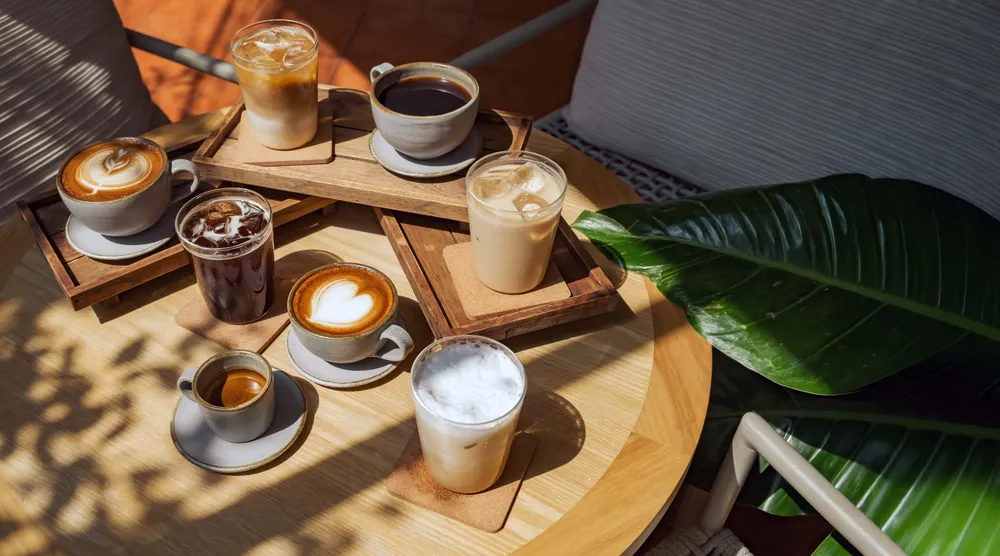 Verschiedene Kaffeevariationen wie Espresso, Cappuccino, schwarzer Kaffee und Eiskaffee auf einem Tisch