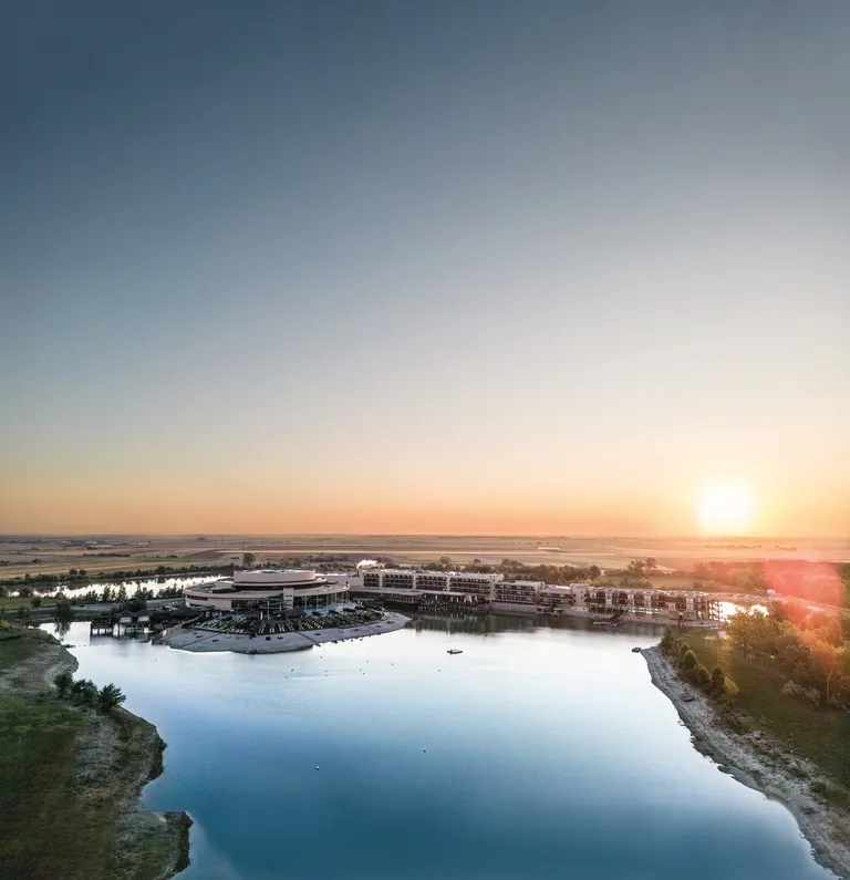 Es ist eine Außenaufnahme der St. Martins Lodge Therme & Spa im burgenländischen Seewinkel bei Sonnenuntergang zu sehen.