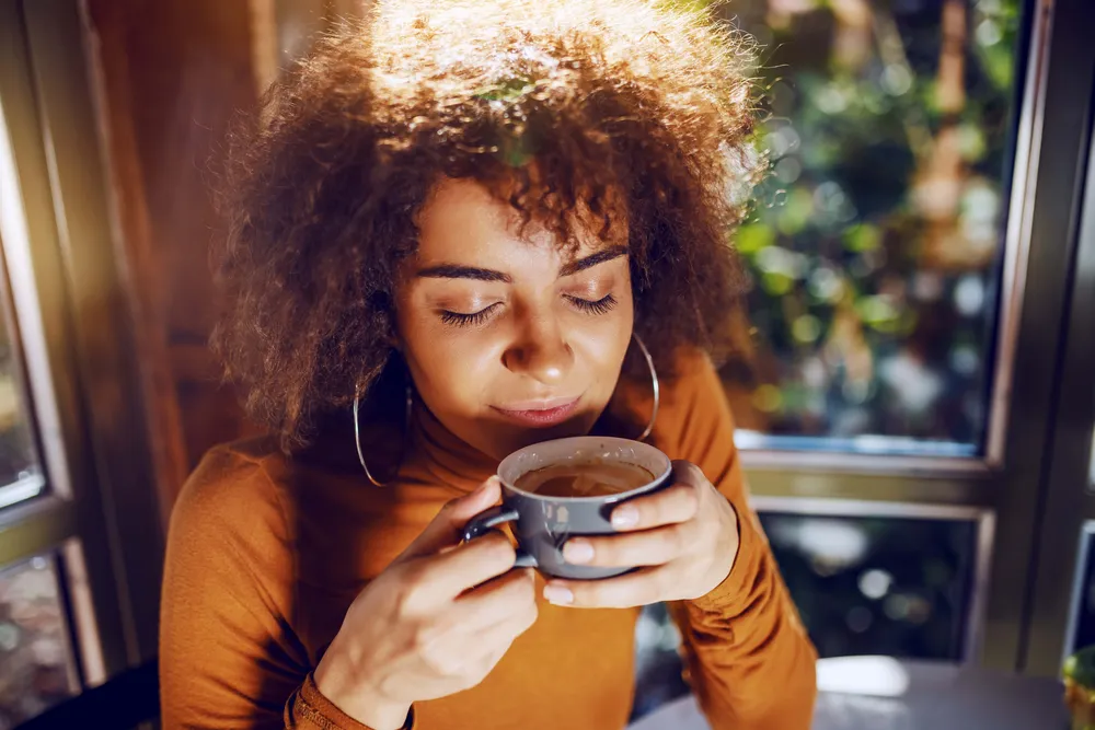 Person genießt eine Tasse frisch gebrühten Kaffee und nimmt das Aroma in entspannter Atmosphäre wahr