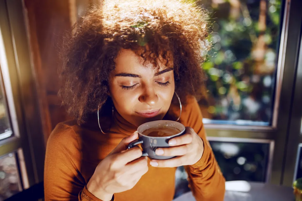 Person genießt eine Tasse frisch gebrühten Kaffee und nimmt das Aroma in entspannter Atmosphäre wahr