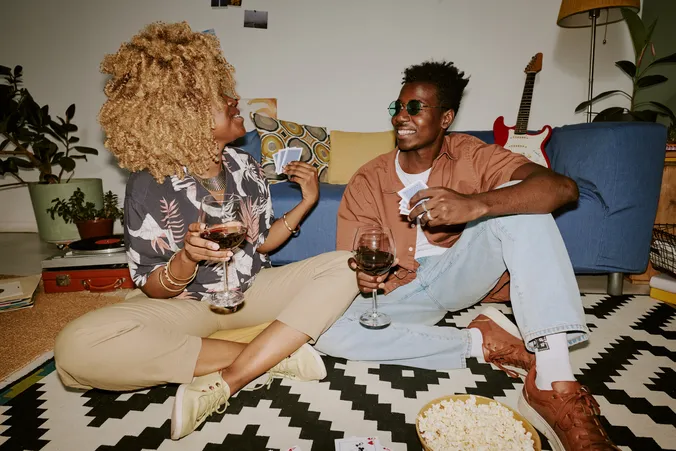 Freunde spielen Karten und trinken Rotwein