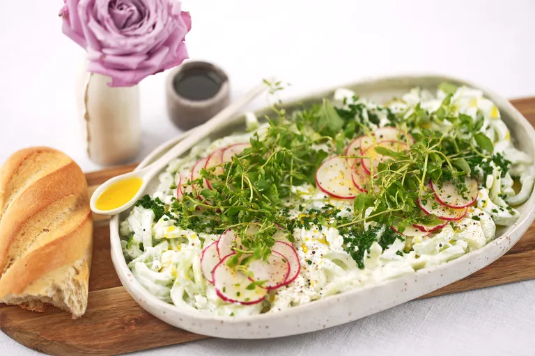 Cremiger Salat mit Radieschen, frischen Kräutern und Kresse auf einer Servierplatte