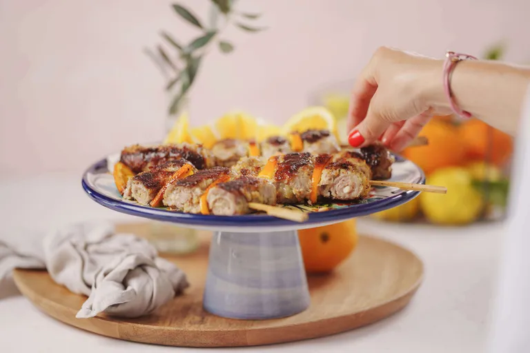 Gegrillte sizilianische Fleischröllchen mit Zitrusfrüchten auf Servierplatte