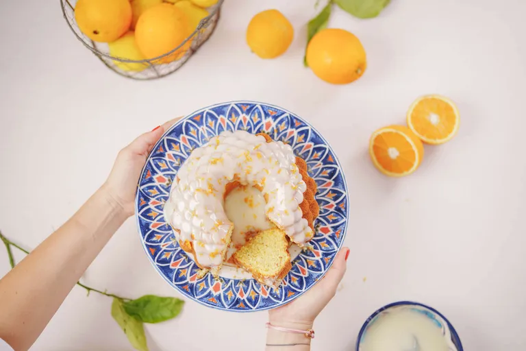 Saftiger Orangen-Gugelhupf mit Zuckerglasur und frischen Orangen