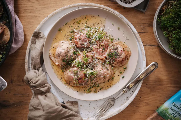 Hausgemachte Ravioli in cremiger Parmesan-Sauce mit frischen Kräutern