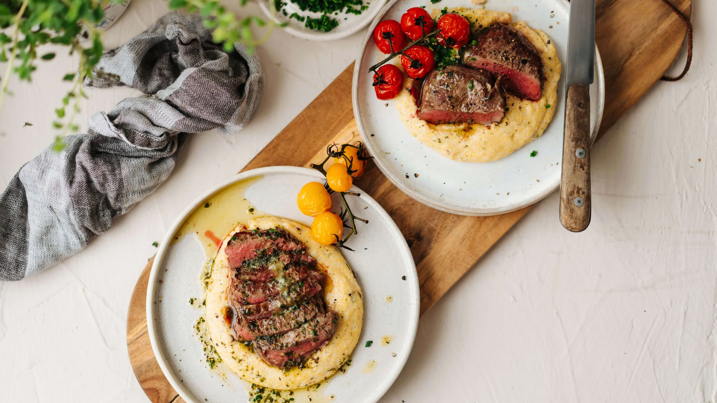 Rosa gebratenes Rindersteak auf cremiger Polenta mit geschmorten Tomaten