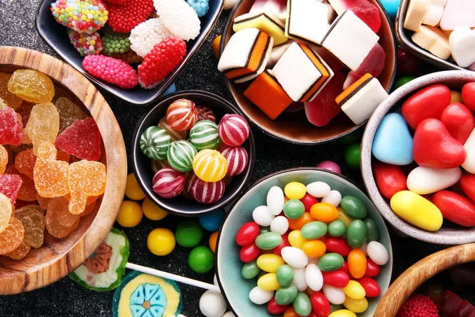 Verschiedene bunte Süßigkeiten wie Fruchtgummis, Bonbons, Lakritz und Schaumzucker in Schalen von oben fotografiert