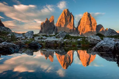 Die Drei Zinnen in den Dolomiten spiegeln sich bei Sonnenuntergang in einem Bergsee