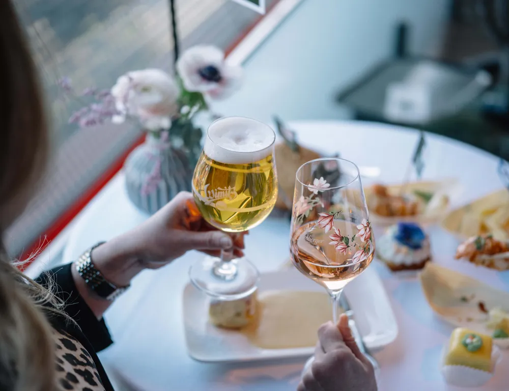 Zwei Personen stoßen bei der Gensusreise im IM82 mit einem Wein- und Bierglas gemeinsam an