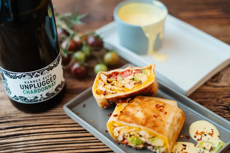 Hähnchen-Burrito mit Gemüse und cremigem Dip, serviert mit Weißwein
