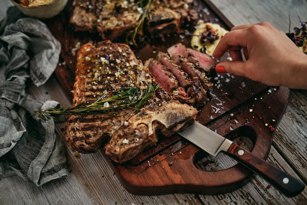 Gegrilltes T-Bone-Steak mit Rosmarin und grobem Meersalz auf rustikalem Holzbrett