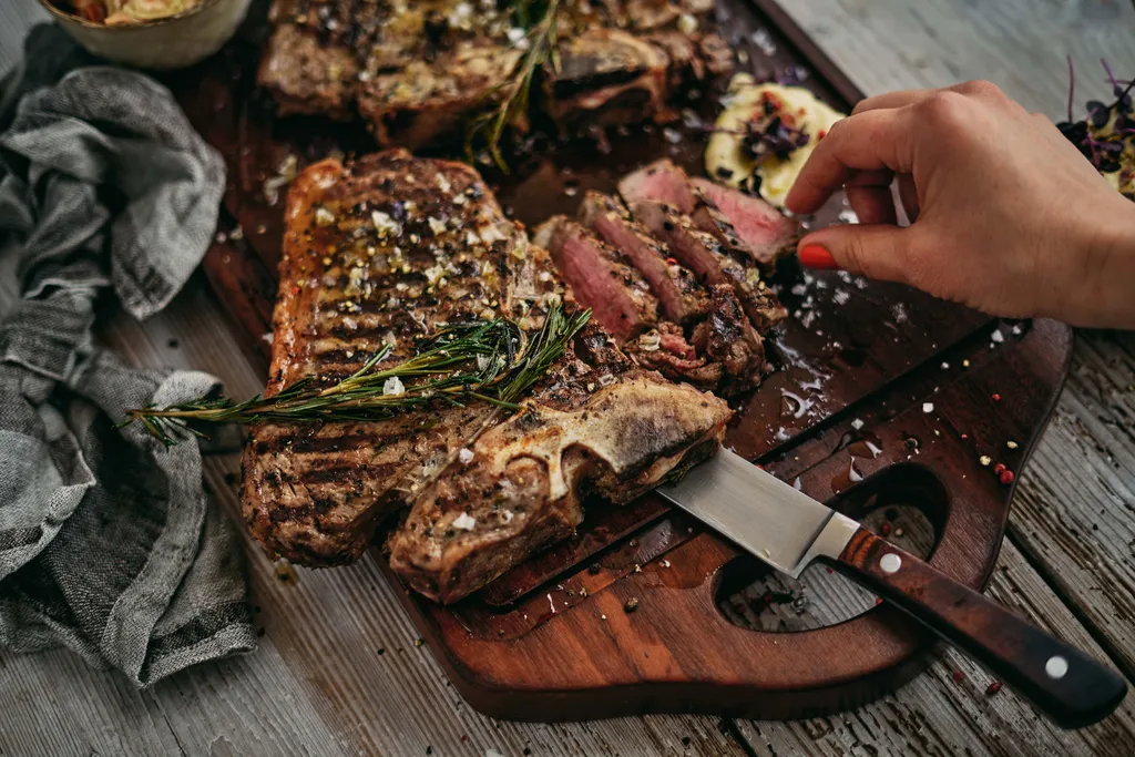 Gegrilltes T-Bone-Steak mit Rosmarin und grobem Meersalz auf rustikalem Holzbrett