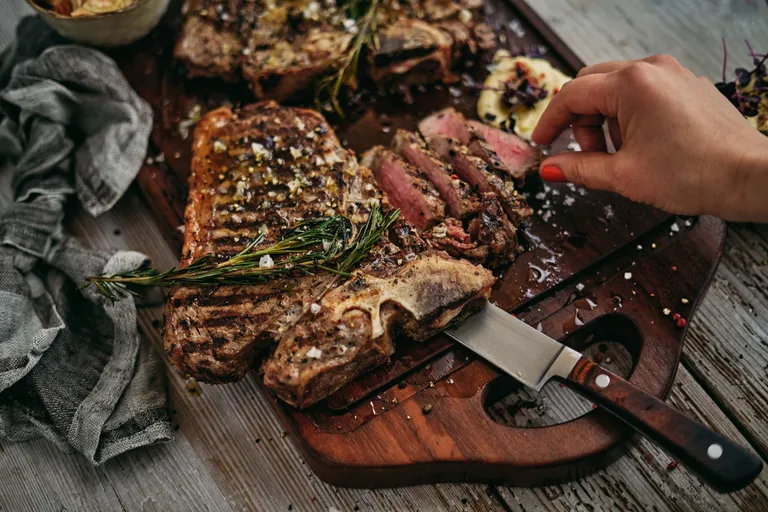 Gegrilltes T-Bone-Steak mit Rosmarin und grobem Meersalz auf rustikalem Holzbrett