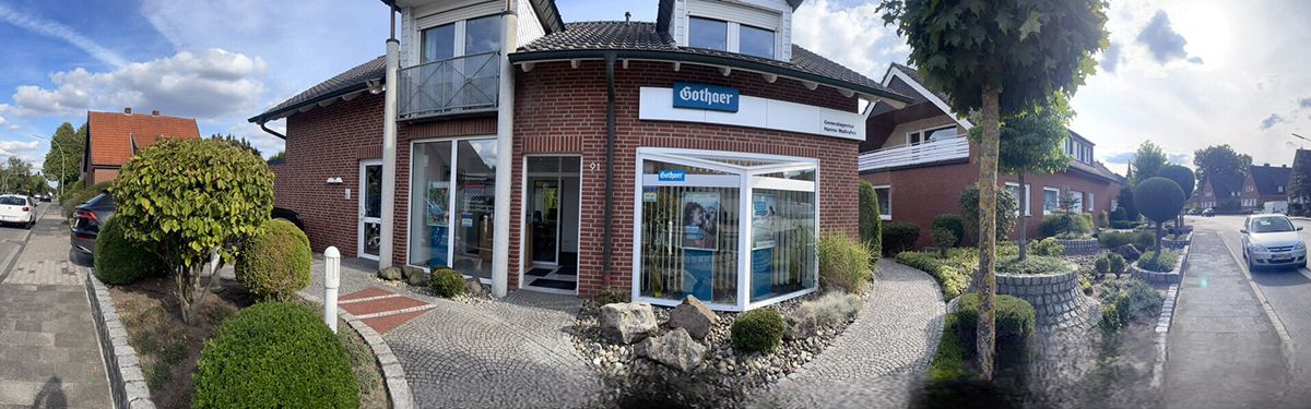 Straßenszene mit rotem Backsteinhaus, Schaufenster, vorgelagertem Garten und parkenden Autos bei teils bewölktem Himmel. - Hanno Wallrafen, BarmeniaGothaer Steinfurt