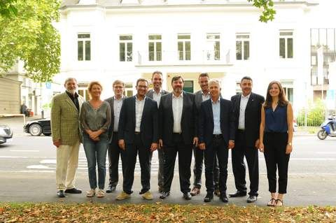 Eine Gruppe von zehn Personen steht draußen auf einer Wiese vor einem weißen Gebäude. Sie lächeln in die Kamera. - Christian Bußmann, BarmeniaGothaer Bonn