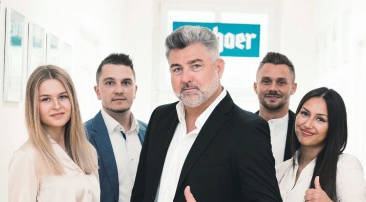 Eine Gruppe von fünf Personen, drei Männer und zwei Frauen, in Geschäftskleidung posiert lächelnd in einem Büroflur vor einem Fenster. - Stefan Sulkowski, BarmeniaGothaer Herten-Westerholt