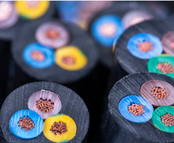 Close-up of cross-sectioned cables showing copper wires inside colored insulation layers of blue, green, yellow, and purple.