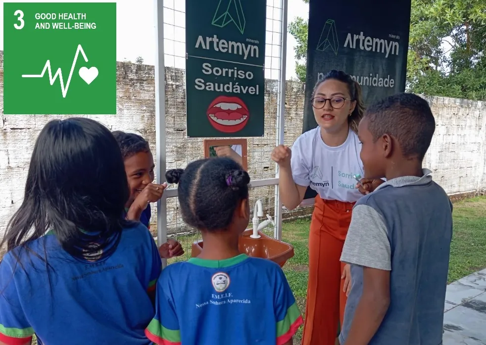 A woman teaches oral hygiene to children at a sink, promoting health and well-being under a banner and Goal 3 symbol for sustainable development.