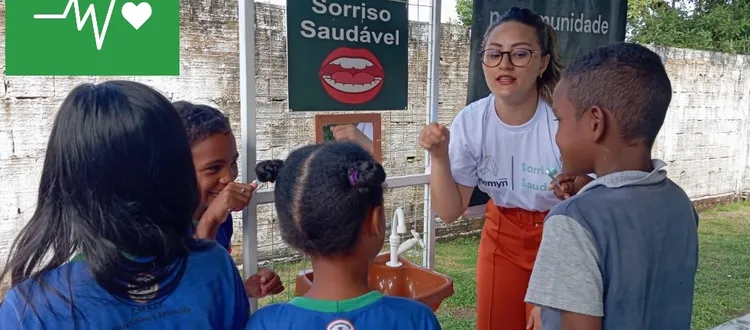 A woman teaches oral hygiene to children at a sink, promoting health and well-being under a banner and Goal 3 symbol for sustainable development.