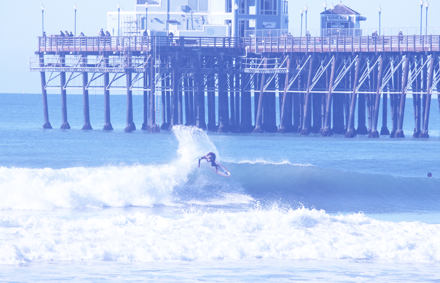 SOCAL DIGITAL MEDIA surfer surfing in the waves in front of a pier