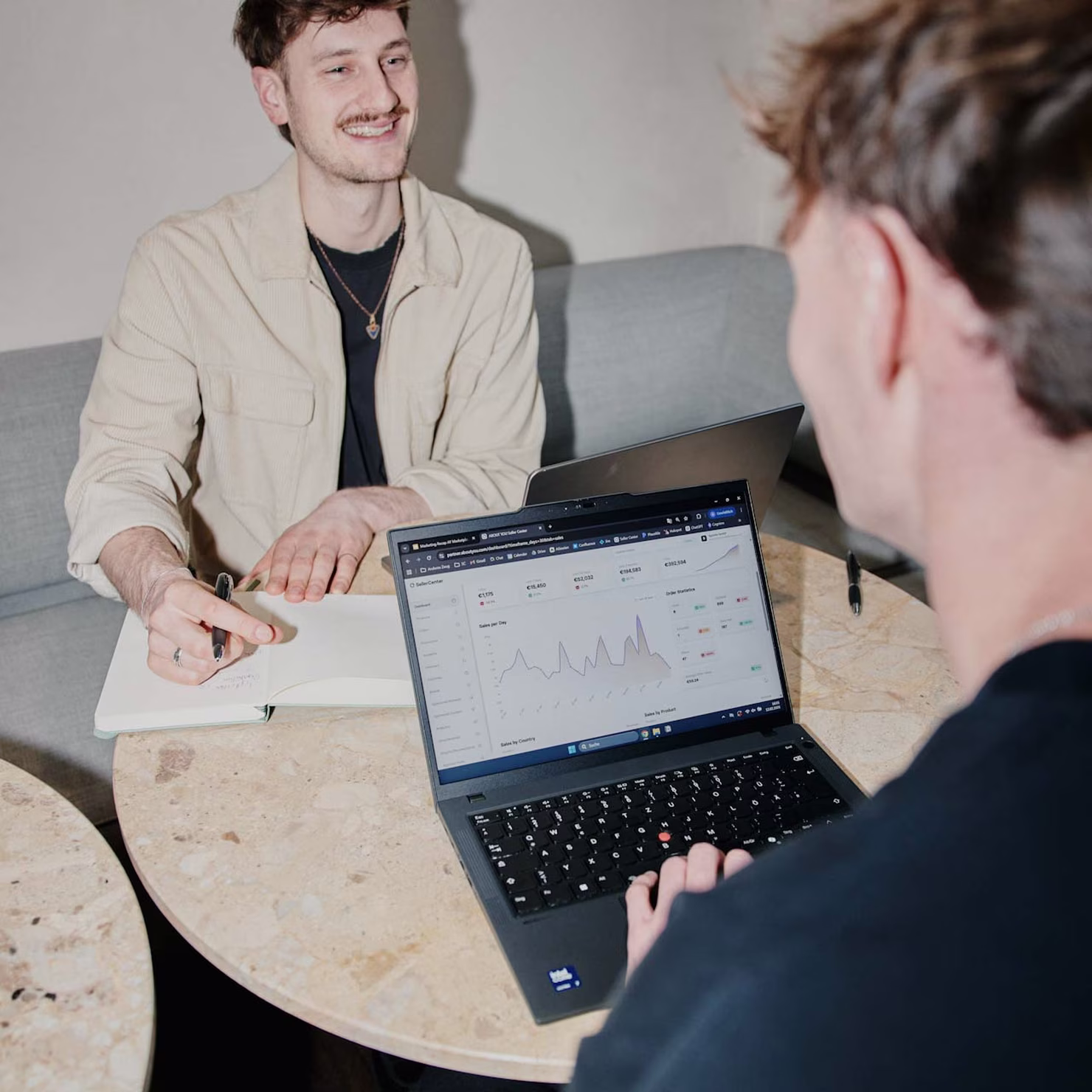 Two people discussing data on a laptop with graphs on screen – collaboration at ABOUT YOU