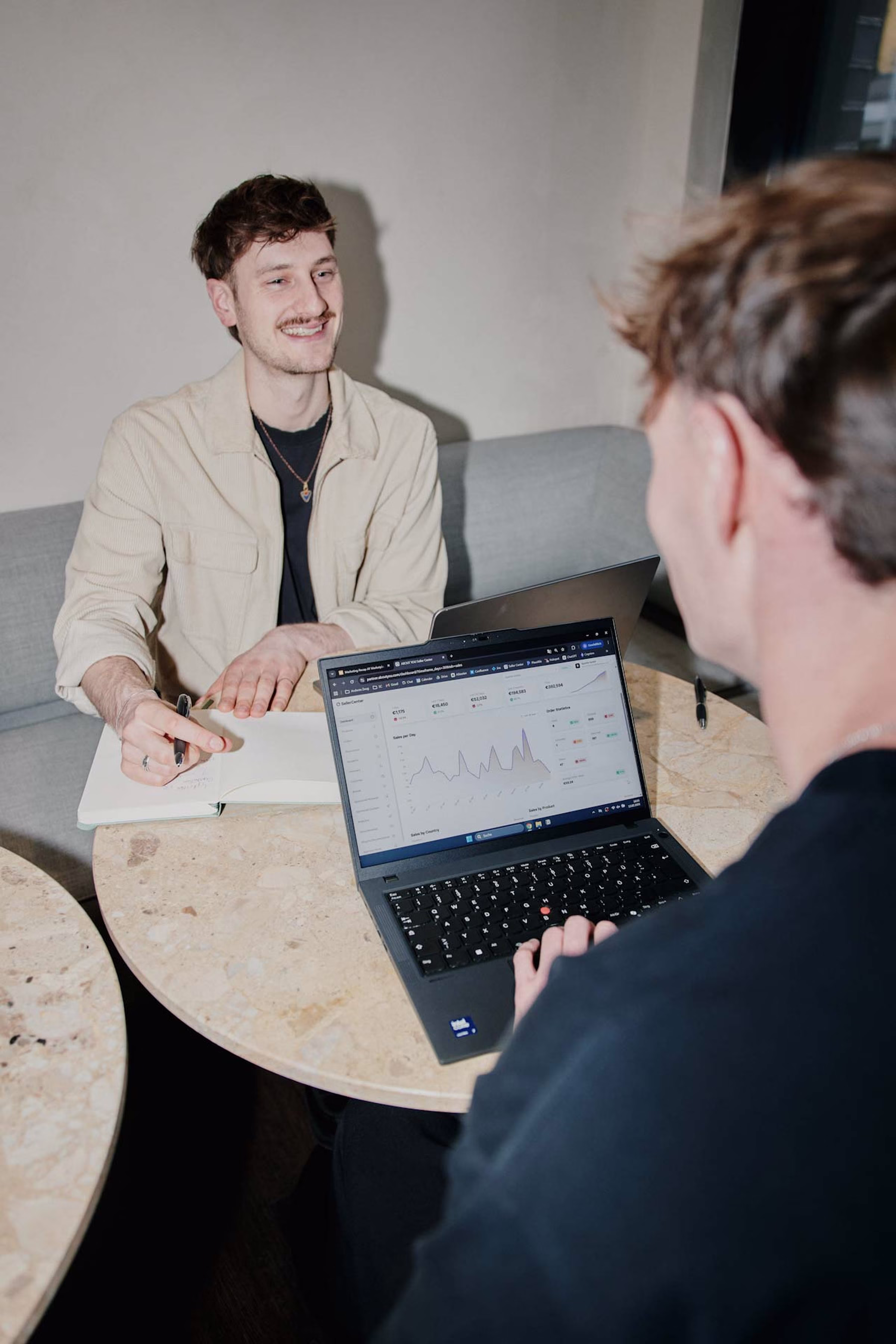 Two people discussing data on a laptop with graphs on screen – collaboration at ABOUT YOU