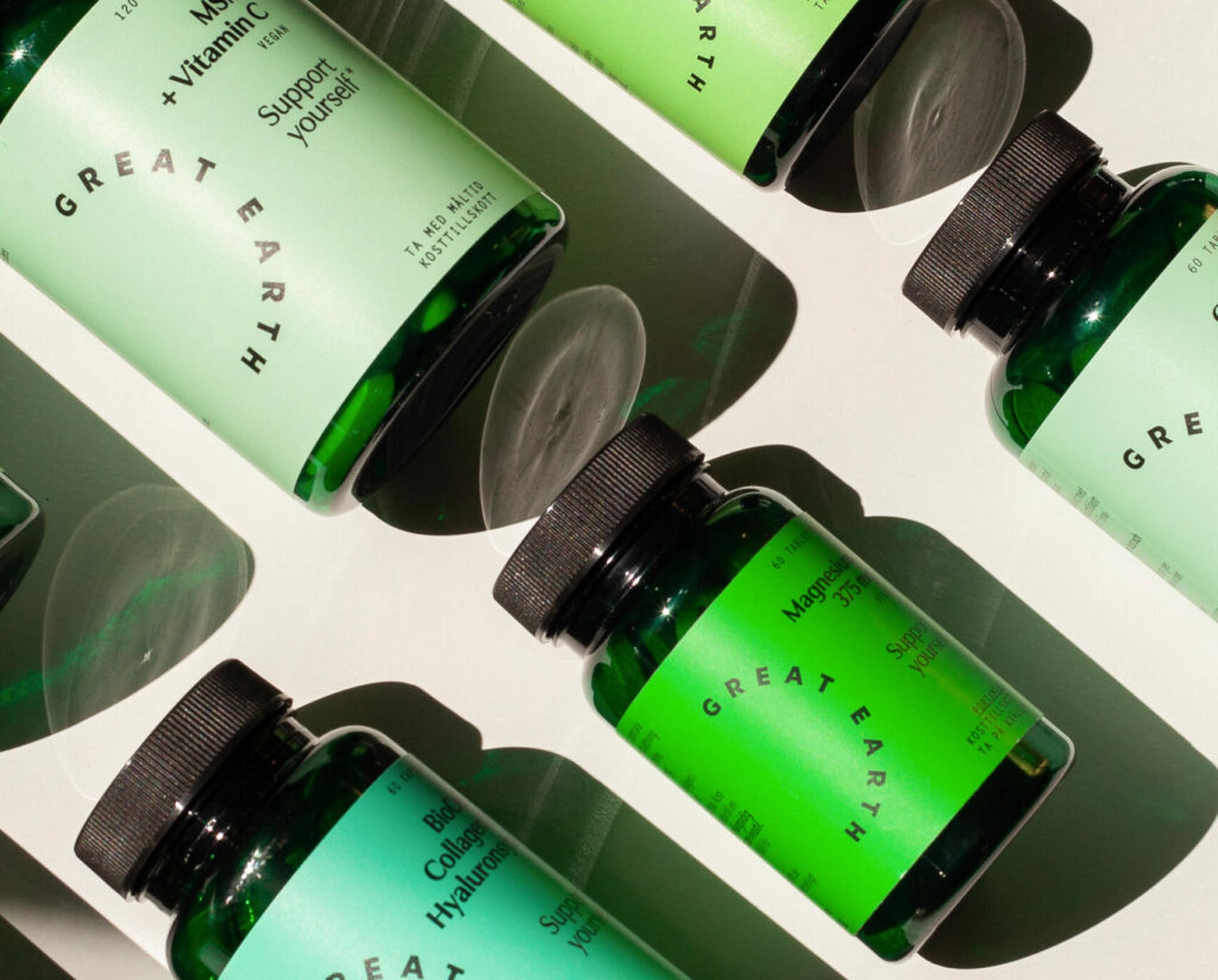 Green Great Earth supplement bottles, including Magnesium, on a white surface in bright sunlight