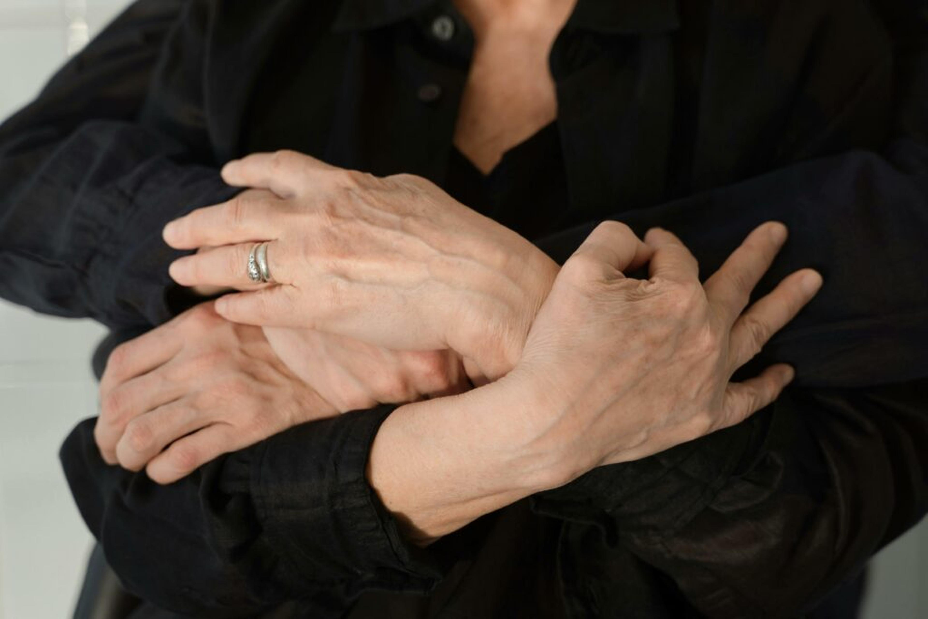 Close-up of two people embracing with hands resting on crossed arms