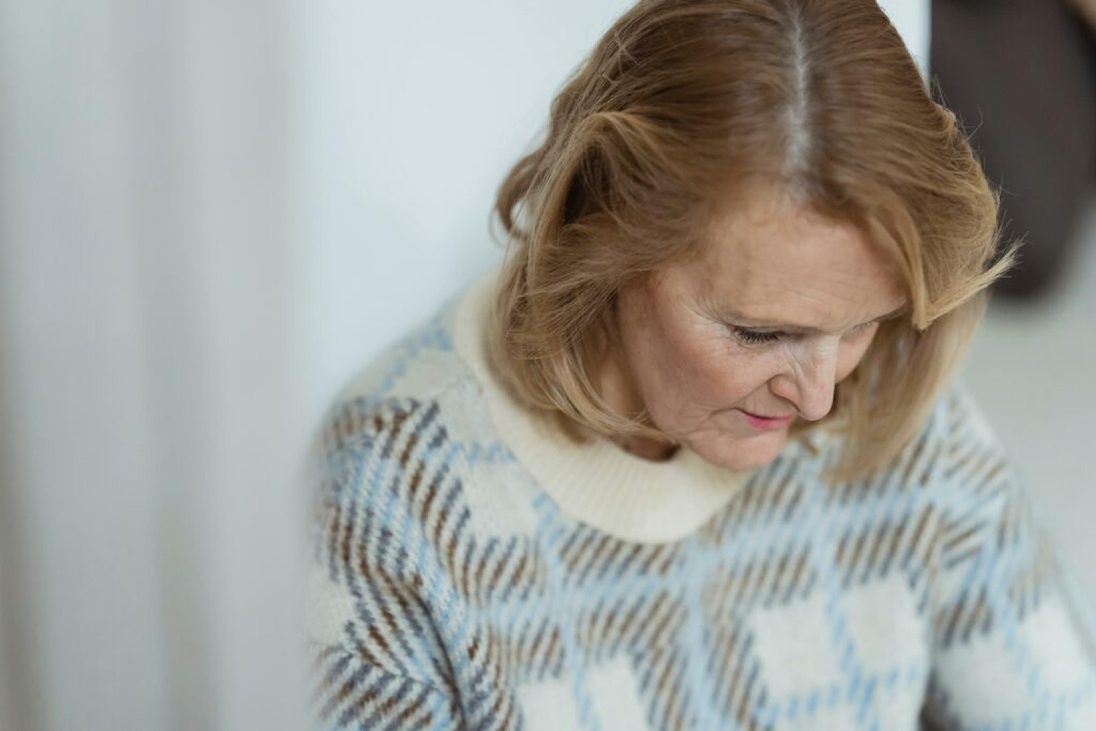 Middle-aged woman looking down thoughtfully, wearing a patterned knit sweater