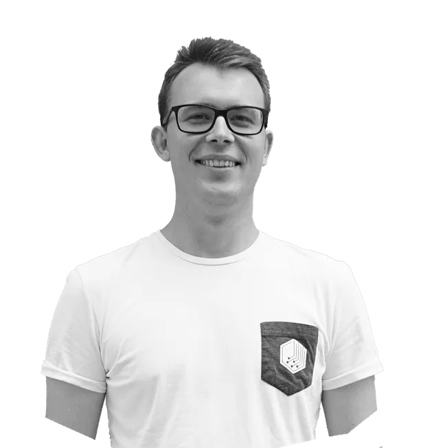 Smiling man in glasses wearing a white t-shirt with a patterned pocket, looking at the camera.