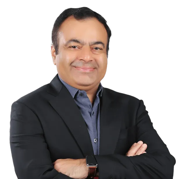 Smiling man in a black blazer and blue shirt, arms crossed.