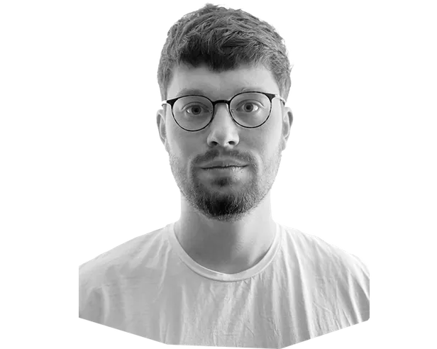 Black and white portrait of a person wearing glasses and a white t-shirt, looking directly at the camera against a plain background.